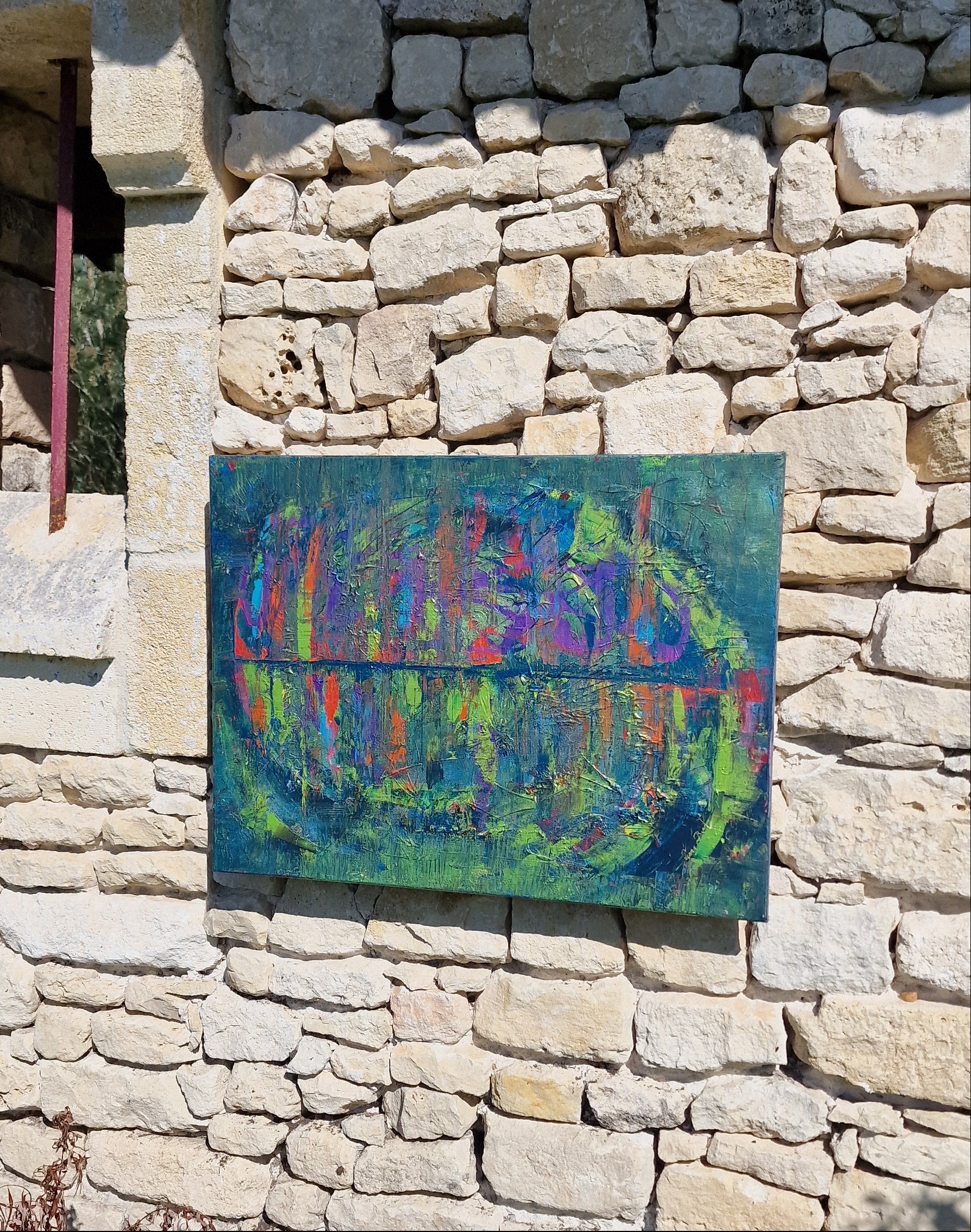 Détail de profil du tableau peinture abstrait moderne Reflets Suspendus™ avec textures épaisses et reflets lumineux sur un mur en pierre en extérieur.