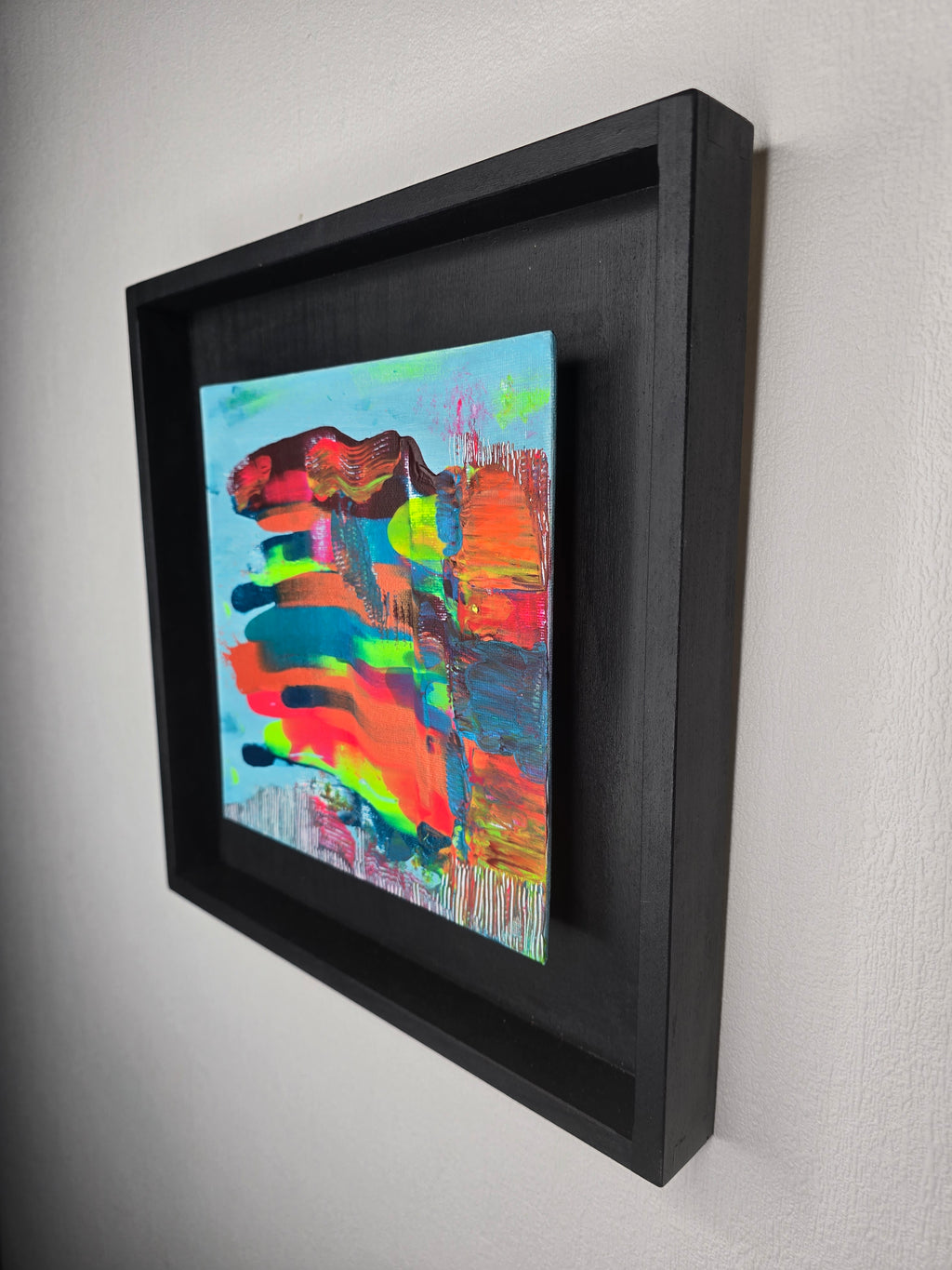 Vue latérale du tableau peinture abstrait contemporain Écrin Néon™ montrant les reliefs de la peinture acrylique et le cadre bois noir